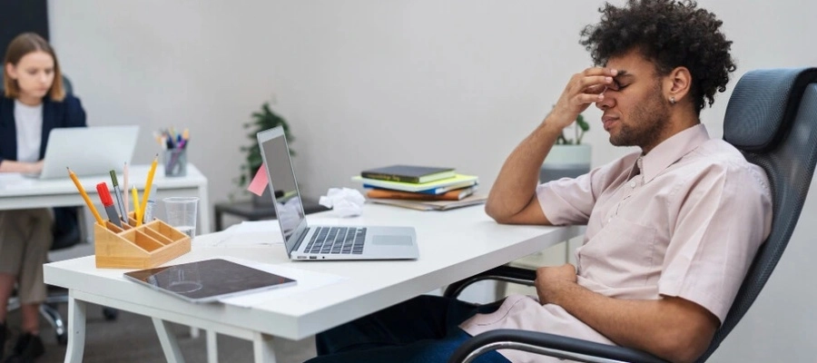 homem cansado em frente ao computador, sem foco e com a m