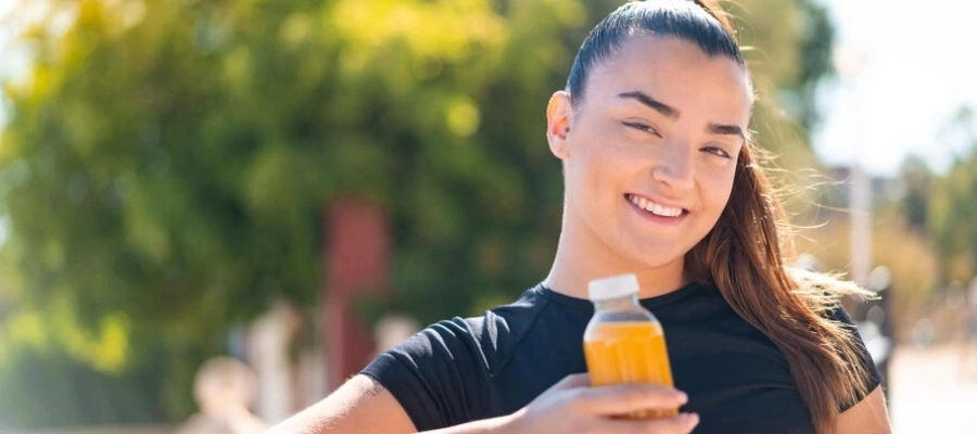 jovem com roupa esportiva segurando uma garrafa com bebida enquanto descansa