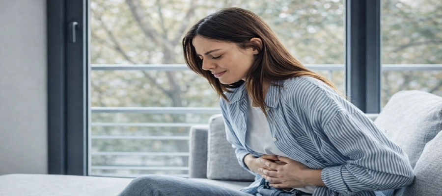 Mulher branca sentada com dor na barriga.