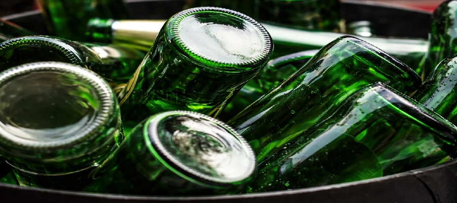 Pilha de garrafas verdes de cerveja vazias no lixo.