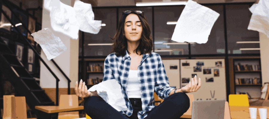 mulher jovem meditando sobre a mesa, cercada de pape?is